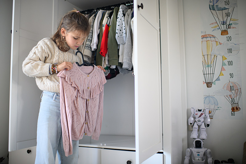 Dievča si skúša oblečenie pred skriňou