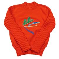 Červený pletený svetr s lesem a lyžařem a žebrovanými rukávy
