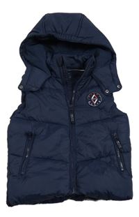 Tmavomodrá šusťáková zateplená vesta s nášivkou a kapucí