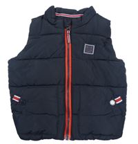 Tmavomodrá prošívaná šusťáková zateplená vesta s nášivkou Next